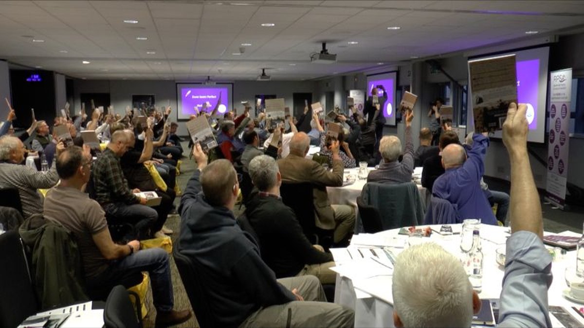 A packed conference room at the National Space Centre with delegates at round tables, many raising their arms towards the stage