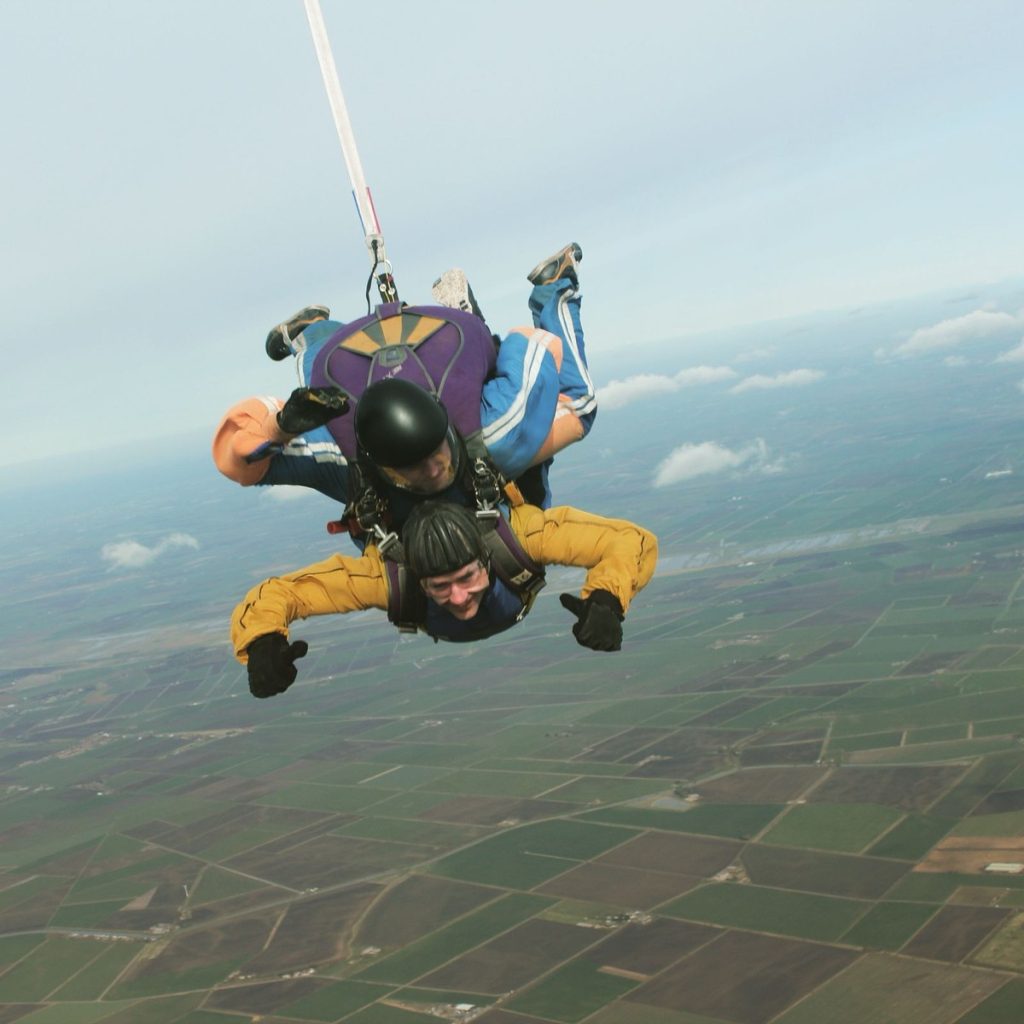 Neil Martin smiling in freefall, seen from above, with the drogue line trailing