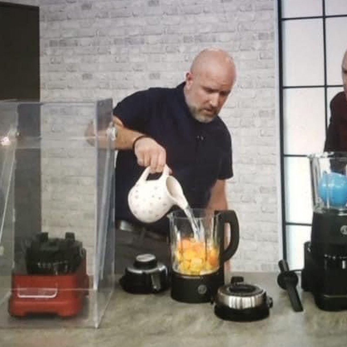 Neil Martin demonstrating kitchen blenders live on a home shopping TV channel, pouring ingredients into a blender jug