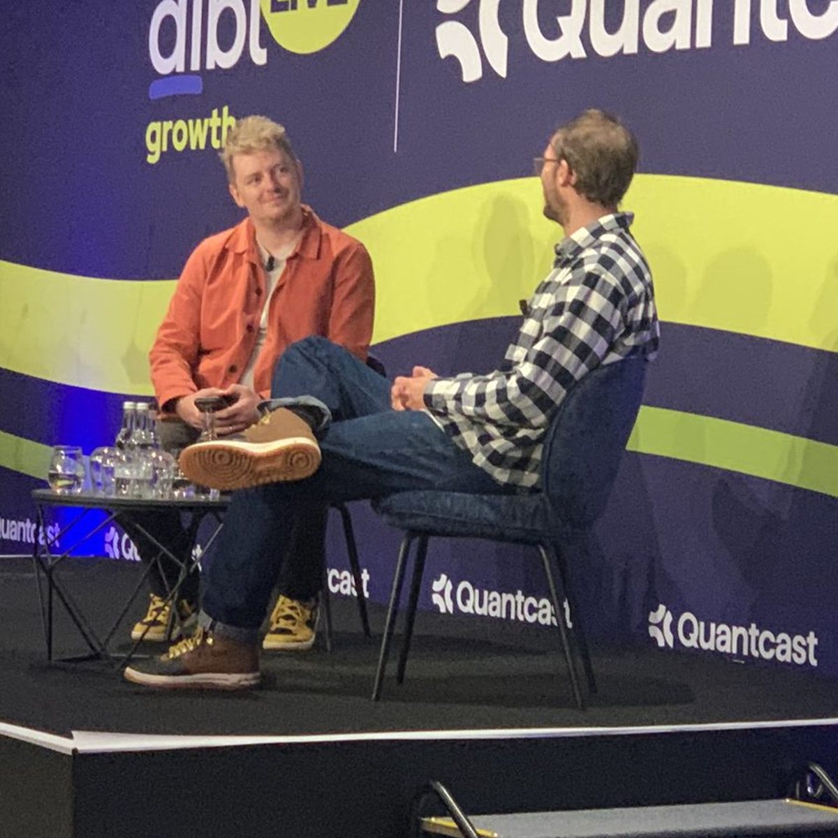 Adam Boita of Ecologi in conversation with Luke Costley-White of Dojo, seated on stage at aiblLIVE London