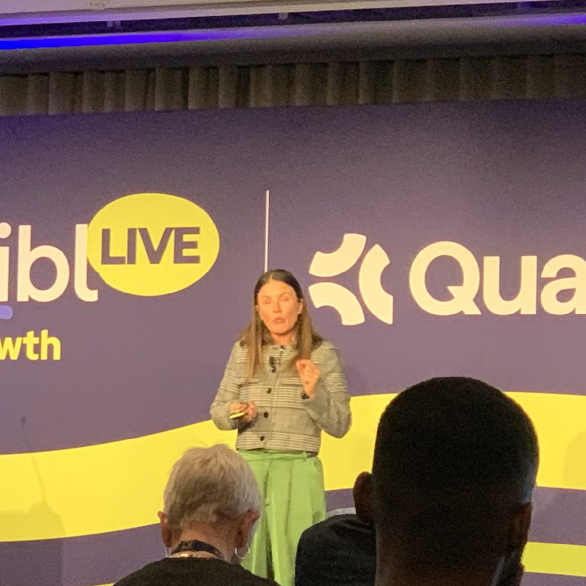 Tracey Pilon of Microsoft Advertising speaking on stage at aiblLIVE London with a headset microphone and clicker